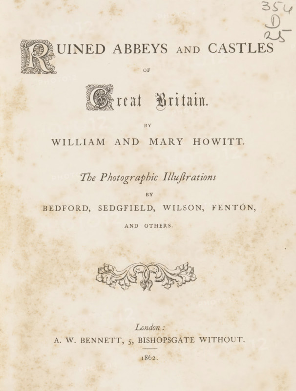 Ruined abbeys and castles of Great Britain, book, name: 'ex libris SFJ', writer (clerical worker): William Howitt, writer (clerical worker): Mary Howitt, publisher: Alfred William Bennett, London, 1862, writer (clerical worker), biological material, paper, leather, albumen print, color on cut, height 227 mm x width 175 mm x thickness 30 mm, An aged page with decorative initials and ornate serif text arranged in centered lines, showing a margin with small brown foxing spots and larger mottled stains across the paper, a pencil scribble in the top right corner, an ornamental floral engraving near the middle, and evenly spaced lines of printed words and names in various typefaces.