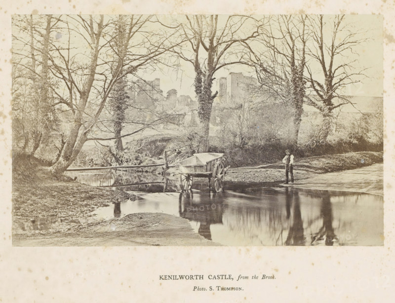 Kenilworth Castle, from the Brook, View of Kenilworth Castle, with a man with a handcart in the foreground, photograph, page, photographer: Stephen Thompson, c. 1854 - in or before 1864, Kenilworth, paper, albumen print, height 100 mm x width 161 mm, Photo opposite title page., hand-cart, ruin of a dwelling, house, castle, A faded sepia photograph shows a shallow stream bordered by grassy banks and leafless trees with tangled branches, several trunks close to the water and some covered in climbing vegetation, a wooden wheeled cart partially in the stream with its reflection visible on the water surface, a man standing at the water's edge wearing a cap and vest with his hands at his waist, a rustic wooden fence and a small footbridge near the trees, and distant stone ruins partially obscured by the trees.