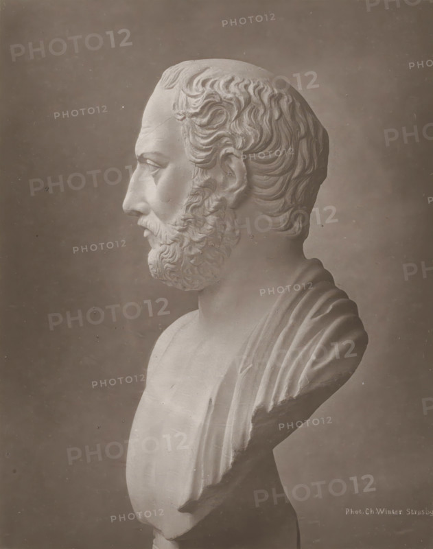 Portrait bust of Thucydides, page, photomechanical print, photographer: Charles David Winter, cliché maker: anonymous, c. 1868 - in or before 1878, paper, carbon print, height 184 mm x width 145 mm, sculpture, chest, bust, A grayscale photograph shows a classical marble bust in profile facing left, featuring a bearded man with wavy hair carved in detailed curls, a prominent nose, closed lips, and a defined jawline; the bust includes draped fabric over one shoulder and a smooth chest, all set against a plain dark background with a light border around the image.