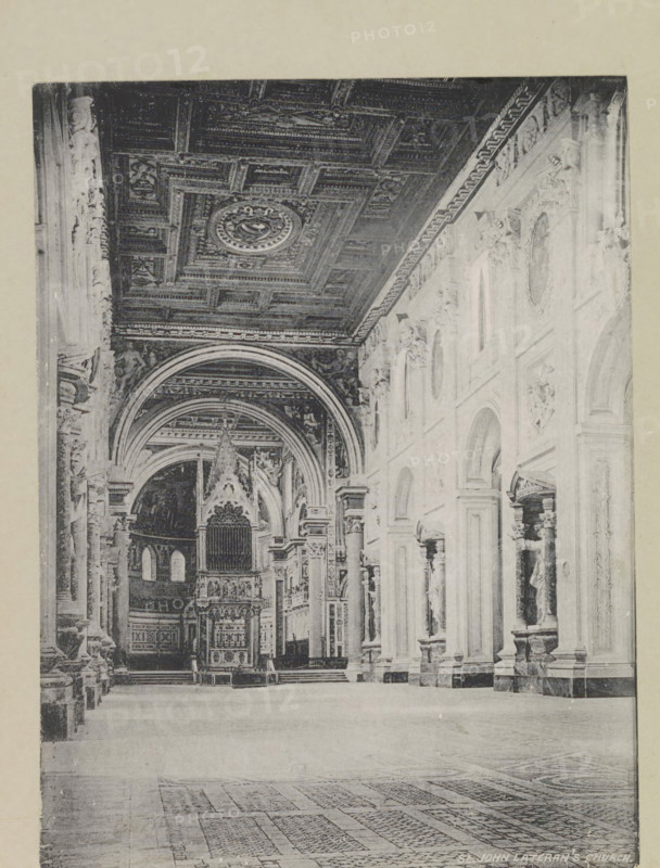 St. John Lateran's church, page, photomechanical print, photographer: Samuel J. Beckett, Sint-Jan Lateran, printmaker: Samuel J. Beckett (possibly), c. 1890 - c. 1900, Samuel J. Beckett, photographer, printmaker, Rome, Sint-Jan van Lateranen, paper, collotype, photoprint, height 203 mm x width 152 mm, interior of church, parts of church interior: aisle, A large interior space with a high decorated ceiling featuring carved panels and a central circular medallion, a series of tall arched openings along a wall with sculpted figures in niches, ornate columns and pilasters, an elevated altar or ornamental structure with pointed decorative gables and an organ-like facade beneath a vaulted arch, patterned floor tiles in the foreground, and carved decorative mouldings and reliefs along the upper walls.