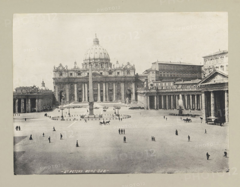 St. Peters. Rome, page, photomechanical print, photographer: Samuel J. Beckett, Vatican City, c. 1890 - c. 1900, paper, collotype, photoprint, height 151 mm x width 203 mm, square, circus, church (exterior), façade (of house or building), St. Peter's Basilica, St. Peter's Square, A wide monochrome view shows a grand classical building with a large central dome flanked by columns and ornate facades, facing an expansive open square. The square features a tall obelisk on a pedestal at its center surrounded by low bollards and lampposts, with a row of colonnades and porticoes extending along one side. Small human figures dot the open area, some walking alone, some in small groups, and a few horse-drawn carriages and a tram are visible near the buildings. Architectural details include statues atop the roofline, arched windows, and a fountain with water near the colonnades. The image has a wide border of neutral-toned background around the photograph.
