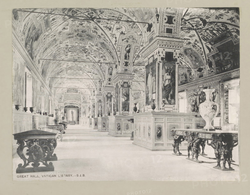 Great hall, Vatican library, page, photomechanical print, photographer: Samuel J. Beckett, Biblioteca Apostolica Vaticana, c. 1890 - c. 1900, Vatican City, paper, collotype, photoprint, height 151 mm x width 197 mm, interior, representation of a building, public library, A long ornate gallery with a vaulted, heavily painted ceiling and decorated arches, lined on both sides by paneled display cabinets and tall pilasters with large framed paintings; ornate wooden tables with carved legs and decorative vases sit along the floor, and sculpted corbels and reliefs appear on the furniture and architectural elements; windows and doorways punctuate the side walls, and the perspective shows the corridor receding toward a distant doorway.