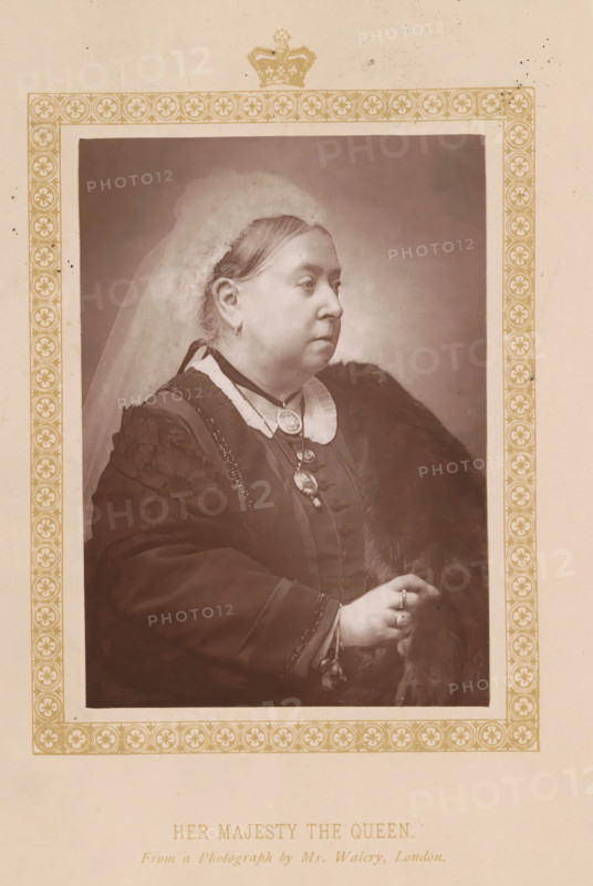 Her Majesty the Queen, page, photomechanical print, photographer: Walery, London, c. 1887 - c. 1892, printmaker, paper, Woodburytype, Woodburytypie, height 119 mm x width 85 mm, Print on frontispiece., Person, Victoria (Queen of the United Kingdom and Empress of India), veil, ruler, sovereign - BB - female ruler, A sepia-toned portrait of a woman shown in profile from the torso up, wearing a light-colored veil over her hair and a dark dress with a high collar and decorative trim, a fur draped over one shoulder, layered necklaces with medallions, earrings, and rings on her hand, set within an ornate rectangular border with repeating circular floral motifs and a crown motif at the top, all on a pale background.
