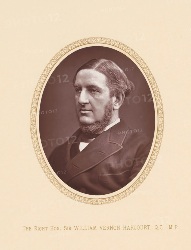 The right hon. Sir William Vernon-Harvourt, QC, MP, page, photomechanical print, c. 1875 - c. 1880, photographer, printmaker, paper, Woodburytype, height 109 mm x width 87 mm, Person, William Vernon Harcourt, politician, eg party leader, An oval sepia portrait of a middle-aged man with neatly combed hair and muttonchop sideburns, wearing a dark suit jacket and a white shirt collar, set against a plain dark background and surrounded by a decorative oval border on a light beige page.
