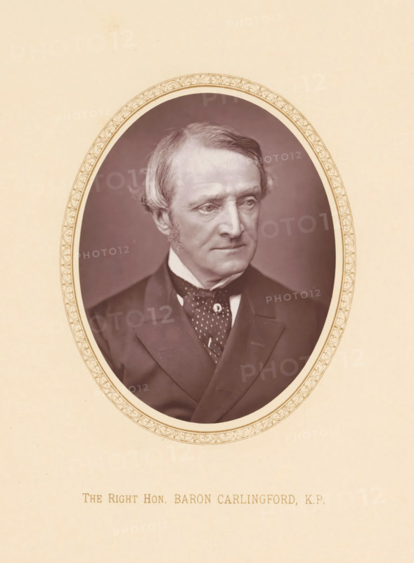 The right hon. Baron Carlingford, KP, page, photomechanical print, c. 1875 - c. 1880, photographer, printmaker, paper, Woodburytype, height 110 mm x width 86 mm, Person, Chichester Parkinson-Fortescue, politician, eg party leader, An oval sepia-toned portrait of an older man with light hair swept to the side and short sideburns, shown from the chest up and wearing a dark suit jacket, a white shirt collar, and a patterned cravat, set within a decorative oval border on a pale background.