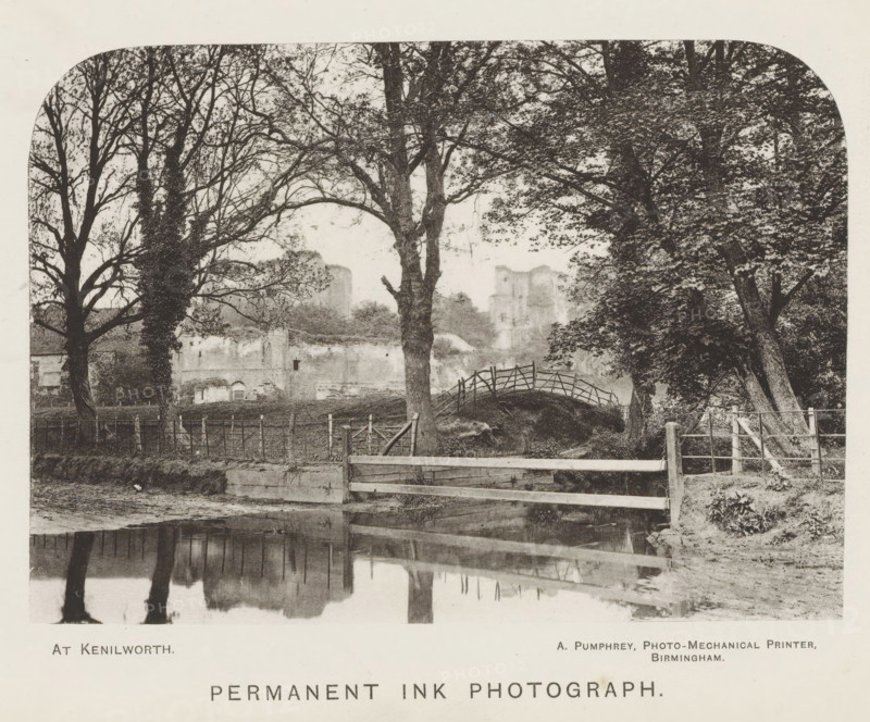 At Kenilworth, page, photomechanical print, inscription: 'Permanent ink photograph', Kenilworth, printmaker: A. Pumphrey, Birmingham, c. 1868 - in or before 1878, photographer, paper, collotype, photoprint, height 100 mm x width 140 mm, landscape with bridge, viaduct or aqueduct, landscape with tower or castle, A sepia-toned landscape showing a row of large trees with bare and leafy branches framing a view of distant ruined stone structures, a small arched wooden footbridge over a grassy mound, a low wooden fence and gate in the foreground beside a calm reflective body of water that mirrors the trees, and a fenced area with posts and wire along the middle ground.