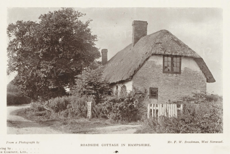 Roadside cottage in Hampshire, page, photomechanical print, photographer: FW Brookman, West Norwood, printmaker: Meisenbach's Autotype Company, c. 1889 - in or before 1899, FW Brookman, Meisenbach's Autotype Company, London, paper, autotype, half-tone engraving, height 92 mm x width 156 mm, cottage, façade (of house or building), A small thatched cottage with textured walls sits beside a winding dirt road, a window with divided panes visible on the upper wall and a smaller window lower down, a brick chimney rises from the roof, and a wooden picket gate stands near overgrown shrubbery and plants in front of the building; a large leafy tree towers to the left, casting shadows over the cottage and surrounding grassy verge under a pale sky.