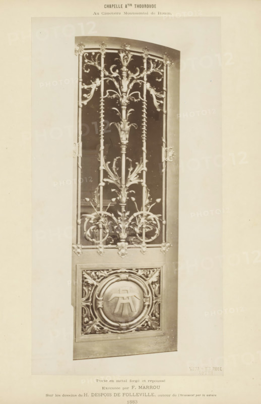 Metal door for a chapel on the Cimetière Monumental in Rouen, Chapelle Atin Thouroude au Cimetière Monumental de Rouen. Porte en metal forgé et repoussé, photograph, page, name: 'Witz & cie Phot. Rouen', inscription: 'Exécutée by F. Marrou Sur les dessins de H. Despois de Folleville, author de l'ornement par la nature', photographer: Witz et Cie., c. 1883 - in or before 1884, Witz et Cie., photographer, paper, albumen print, height 265 mm x width 142 mm, gate, entrance, A tall ornate metal door panel with decorative wrought elements including vertical bars, spiral-twisted rods, and stylized floral and foliate motifs forming symmetrical patterns, a central vertical stem with branching leaves and scrolls, circular ornamental frames near the lower section enclosing a raised emblem-like form, and a rectangular surround with carved corner details, all shown against a plain light background.