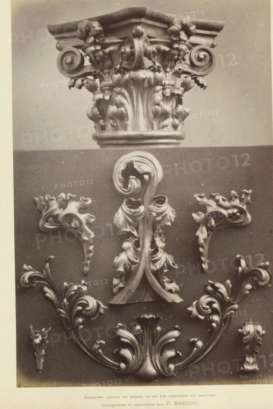 Diverse pièces en plomb et en fer repoussé au martean, Decorative ornaments in lead and iron, depicting a capital and leaf motifs, photograph, page, inscription: 'Composées et exécutées by F. Marrou.', name: 'Witz & cie Phot. Rouen', photographer: Witz et Cie., c. 1874 - in or before 1884, paper, albumen print, height 267 mm x width 176 mm, ornament derived from plant forms, capital (, column, pillar), A photographic display shows a carved architectural capital at the top with ornate acanthus leaves and volutes, resting above a textured backdrop that holds a central vertical ornamental scroll with curled leaf forms and two symmetrical side motifs featuring flowing, stylized foliage; additional decorative foliate elements with curved, layered leaves appear toward the bottom, all rendered in a monochrome tone with subtle surface speckling.