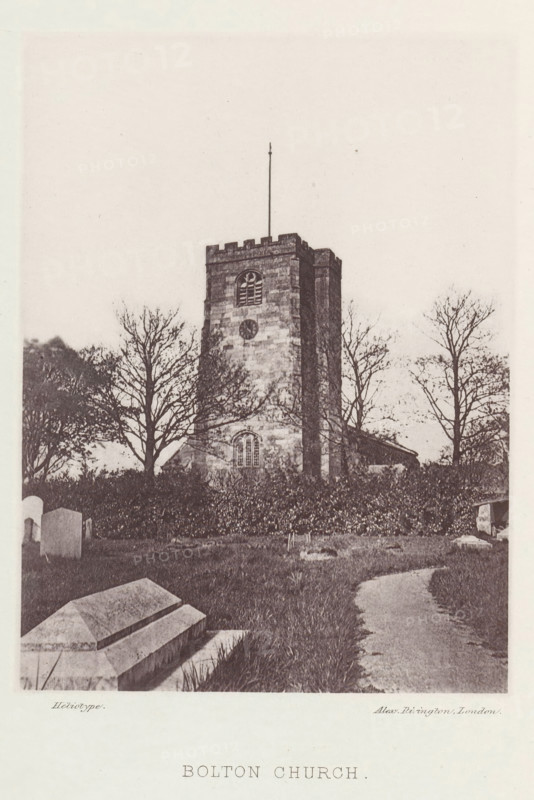 View of the Holy Trinity Church in Bolton-le-Sands, Bolton church, page, photomechanical print, photographer: Alex Rivington, Bolton-le-Sands, London, c. 1870 - in or before 1880, paper, heliotype, height 155 mm x width 114 mm, church (exterior), parts of church exterior and annexes: tower, A stone church tower rises from a grassy churchyard, its battlemented top and narrow vertical flagpole visible against a pale sky, with a small arched window and circular opening on the tower face; leafless trees stand around the tower, their branches silhouetted, and hedges border the base of the building; in the foreground are stone tombs and a winding dirt path through the grass leading toward the church.
