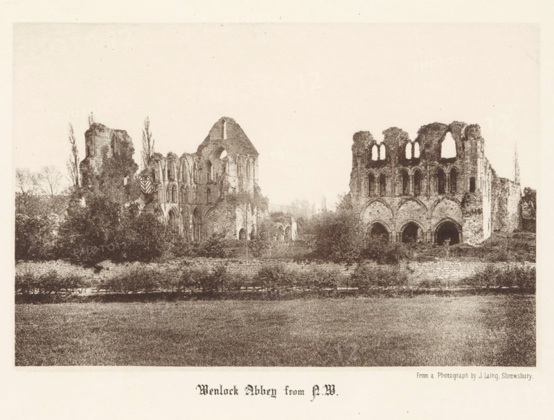 Wenlock Abbey from NW, View of the ruins of Wenlock Priory, page, photomechanical print, photographer: J. Laing, Wenlock Priory, cliché maker: anonymous, c. 1867 - in or before 1877, Shropshire, Much Wenlock, paper, collotype, photoprint, height 125 mm x width 189 mm, ruin of church, monastery, A wide sepia-toned image showing the ruins of a large stone abbey set behind a low wall and a strip of grass in the foreground, with two main ruined sections separated by vegetation; the left section features tall arched windows, partial walls, and a gabled roofline with surrounding trees and shrubs, while the right section shows a façade with large arched openings and upper window arches, all set against a pale sky.