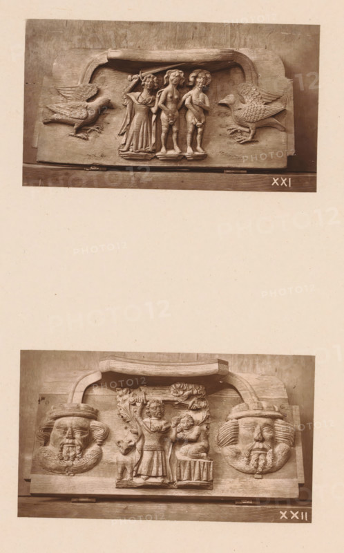 Two carvings in Worcester Cathedral, page, photomechanical print, Above an angel chases Adam and Eve from Paradise between two birds, below Abraham sacrifices Isaac between two faces., number: 'XXI, XXII', c. 1863 - in or before 1873, paper, Woodburytype, height 306 mm x width 244 mm, interior of church, an angel chases Adam and Eve out of paradise with a (flaming) sword, the sacrifice of Isaac (Genesis 22), carving, applied arts, A photograph of two carved wooden panels mounted one above the other on a pale background, each panel featuring a central raised scene flanked by decorative elements; the upper panel shows three standing human figures under a curved canopy with a large bird with outstretched wings carved to each side, the figures wearing draped garments and the central figures appearing unclothed from the waist up, with carved bases beneath their feet; the lower panel shows a central standing figure holding an object above a smaller seated figure, flanked by two large carved ...