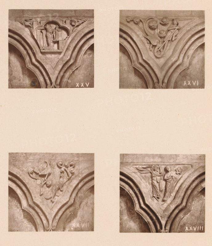 Four woodcarvings in an arcade of Worcester Cathedral, page, photomechanical print, Top left a bishop with a model of a church, top right a figure fighting a serpent, bottom left a rooster and a fox, bottom right the Annunciation., number: 'XXV, XXVIII', c. 1863 - in or before 1873, paper, Woodburytype, Woodburytypie, height 305 mm x width 244 mm, interior of church, the Annunciation: Mary standing, carving, applied arts, patron handing over model of church (or chapel), Four close-up photographs of carved stone arch decorations arranged in a two-by-two grid on a pale background; each photograph shows a pointed arch profile with layered moldings and a carved triangular spandrel above the arch. The top-left photograph depicts a carved scene with a robed figure standing beside architectural forms and a rectangular element, flanked by ornamental details and sculpted foliage at the upper corners. The top-right photograph shows a carved figure kneeling or leaning with flowing drapery amidst ...