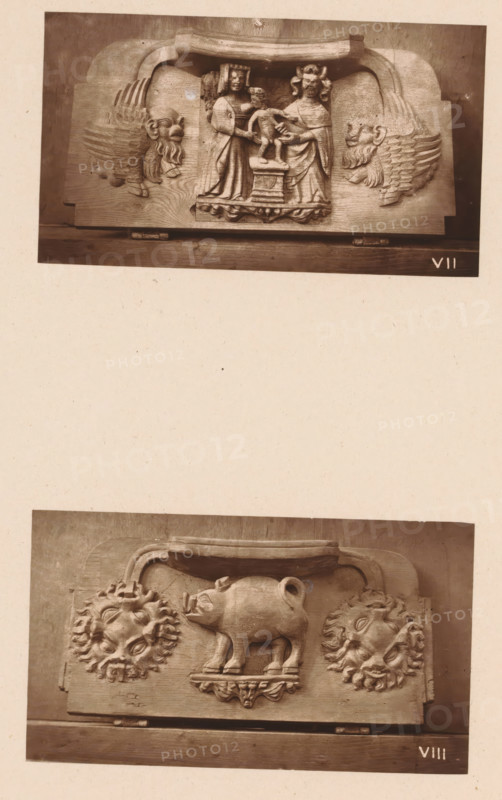 Two woodcarvings in Worcester Cathedral, page, photomechanical print, Above a couple with a nursing child (presumably Joseph and Mary with Christ) between two fantastical creatures, below a boar between two stylized suns., number: 'VII, VIII', c. 1863 - in or before 1873, paper, Woodburytype, Woodburytypie, height 306 mm x width 244 mm, interior of church, boar (male pig), nursing, suckling, carving, applied arts, A photograph shows two horizontal carved wooden panels mounted vertically on a pale background, the upper panel depicting three carved humanlike figures standing on a small raised platform flanked by stylized winged lion heads, and the lower panel showing a carved pig standing on a small pedestal with two ornate circular sunburst faces to its sides; both panels have decorative molding along their top edges and visible wood grain and mounting hardware at their bottoms.