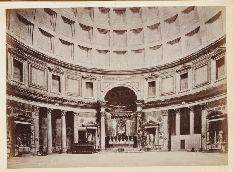 Interior of the Pantheon in Rome, photograph, page, Pantheon, c. 1850 - in or before 1860, photographer, Rome, paper, albumen print, height 98 mm x width 135 mm, interior of church, parts of church interior: dome, A wide interior view showing a large curved wall topped by a coffered dome with recessed square panels, beneath which a continuous entablature runs above a row of rectangular framed panels and niches with triangular pediments; tall fluted columns with decorated capitals stand along the lower wall, separating doorways and niches containing statues and sculptural reliefs, and a central arched niche houses an ornate altar area with balustrade, sculpted figures, and architectural ornamentation, all rendered in a monochrome photographic tone.