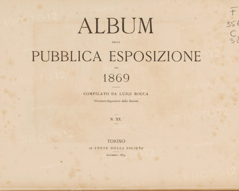Album della pubblica esposizione del 1869, book, compiler (person in literature): Luigi Rocca, 1869, compiler (person in literature), textile materials, pasteboard, paper, linen (material), printing, albumen print, engraving, height 226 mm x width 303 mm x thickness 10 mm, A faded, cream-colored page with dark serif headings arranged vertically, showing a large centered word at the top, a line of smaller centered text beneath it, a wide uppercase phrase across the upper middle, and a prominently centered numeral below that, all printed in a dark ink; the page has visible age spots and scattered brown foxing marks, faint horizontal creases, and a narrow handwritten sequence in the right margin; additional smaller centered lines of printed text appear below the numeral, and the lower half of the page is mostly blank with a few isolated stains.