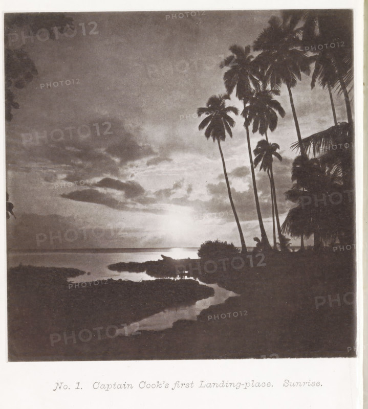 View of a beach with palm trees at sunrise on Tahiti, Captain Cook's first landing-place. Sunrise, page, photomechanical print, number: 'No. 1.', photographer: Henry Stuart-Wortley, Tahiti, cliché maker: Meisenbach's Autotype Company, printer (person): Meisenbach's Autotype Company, 1880, Henry Stuart-Wortley, Meisenbach's Autotype Company, photographer, French Polynesia, paper, collotype, photogravure, height 135 mm x width 135 mm, Print opposite title page., beach, trees: palm-tree, A grayscale coastal scene showing a horizon over calm water with a bright circular light near the horizon and reflections on the water, cloud formations in the sky, a shoreline with dark rocky foreground shapes and a narrow water channel leading inward, silhouetted tall palm trees with visible fronds clustered on the right side, smaller shrubs and vegetation near the shore, and partial overhanging leaves at the upper corners.