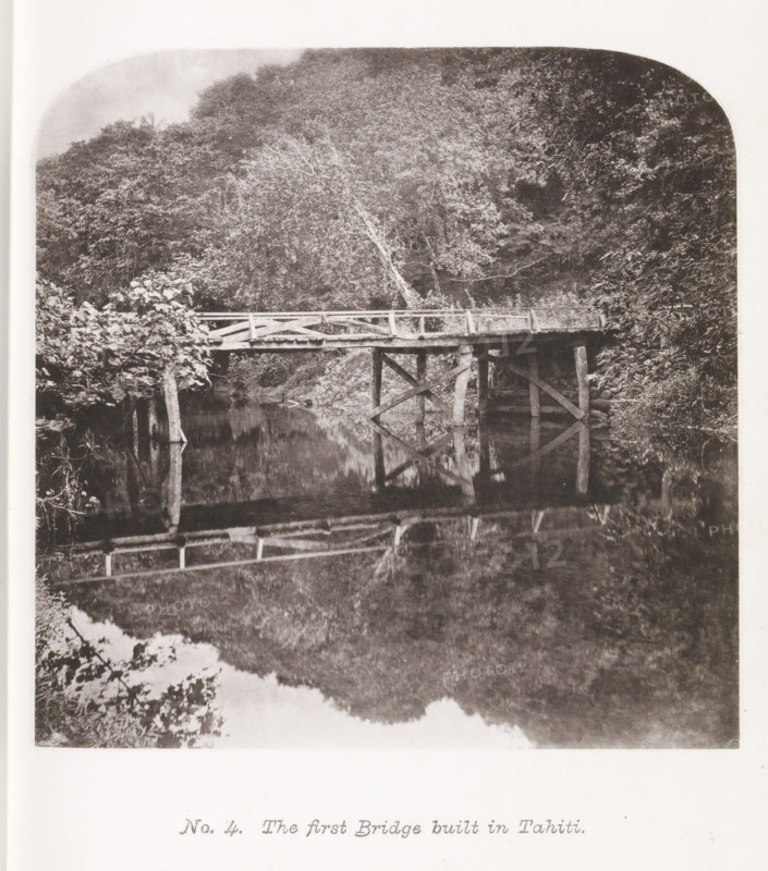 View of a bridge on Tahiti, The first Bridge built in Tahiti, page, photomechanical print, number: 'No. 4.', photographer: Henry Stuart-Wortley, Tahiti, cliché maker: Meisenbach's Autotype Company, printer (person): Meisenbach's Autotype Company, 1880, Meisenbach's Autotype Company, photographer, French Polynesia, paper, collotype, photoprint, height 138 mm x width 139 mm, bridge, A black and white photograph of a wooden bridge spanning a calm body of water, with wooden posts and cross-bracing supporting a plank deck and simple railing, surrounded by dense foliage and trees on both banks, one tree leaning toward the bridge, and the bridge and nearby vegetation reflected in the water below.