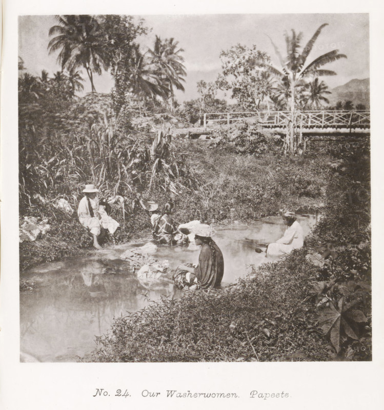 Our Washerwomen. Papeete, Women washing clothes in a river near Papeete, page, photomechanical print, number: 'No. 24.', photographer: Henry Stuart-Wortley, Papeete, cliché maker: Meisenbach's Autotype Company, printer (person): Meisenbach's Autotype Company, 1880, Meisenbach's Autotype Company, photographer, French Polynesia, Tahiti, paper, collotype, photoprint, height 134 mm x width 135 mm, trees: palm-tree, building or outbuilding where laundry is done, A sepia photograph showing a riverside scene with several people sitting at the water's edge washing cloths, surrounded by dense tropical vegetation including tall palm trees and broad-leaf plants, a wooden bridge crossing the stream in the background, reflections of foliage and figures visible in the water, and garments and bundles placed on the riverbank.
