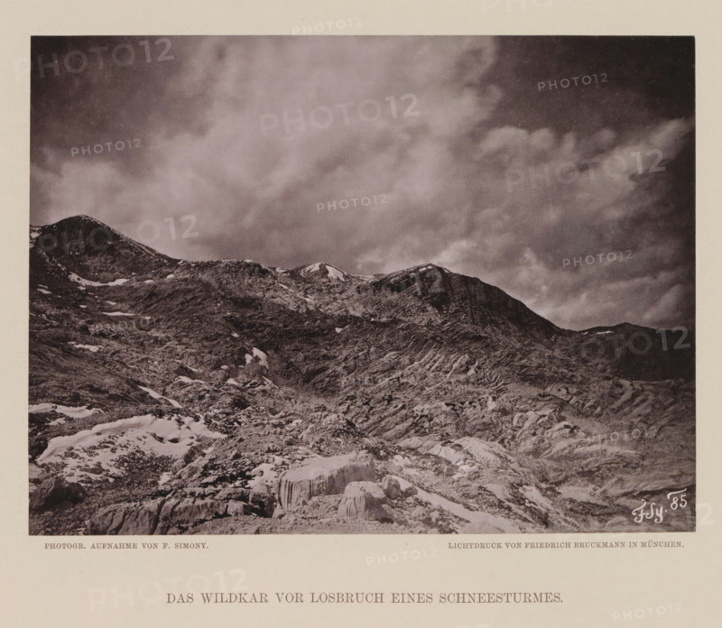 View of the Wildkarspitze, Das Wildkar vor losbrüch eines Scheesturmes, page, photomechanical print, number: 'IX.', photographer: Friedrich Simony, Austria, cliché maker: Friedrich Bruckmann, Vienna, publisher: Eduard Hölzel, c. 1879 - in or before 1889, Lower Austria, paper, collotype, photoprint, height 143 mm x width 190 mm, mountain-top, peak, Tirol, Wildkarspitze, A monochrome photograph shows a rocky mountain landscape with craggy ridges and patches of snow scattered across rough textured slopes, the foreground featuring fractured rocks and a prominent ice formation, and the upper portion dominated by a cloudy sky with varying tonal clouds above the mountain peaks.