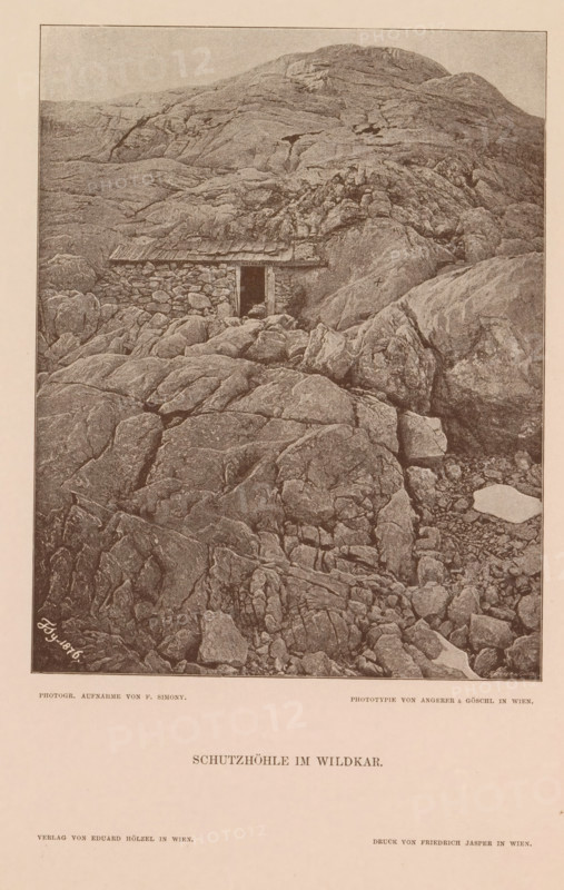 Schutzhöhle im Wildkar, Shelter on the Wildkarspitze, page, photomechanical print, number: 'XIV.', photographer: Friedrich Simony, Tirol, cliché maker: Angerer & Göschl, C., Vienna, publisher: Eduard Hölzel, 1876, Lower Austria, Tyrol, paper, autotypie, height 196 mm x width 154 mm, hut, cabin, lodge, mountain-top, peak, Wildkarspitze, A sepia-toned image showing a rocky mountainside with layered, weathered rock formations filling most of the frame and a low stone shelter built into the rock face with a small dark doorway and a simple roof, surrounded by uneven boulders and crevices, with steeper rock slopes rising behind the shelter and more broken rock and pebble-strewn ground in the foreground.