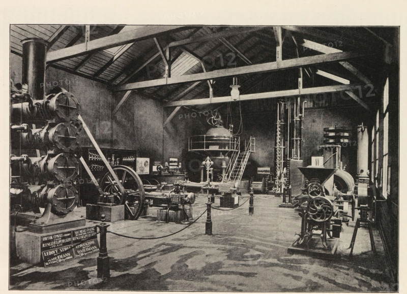 Pohled do vnitr pavilonu firmy Novak a Jahn v Praze, Interior of an engine room with an exhibition of Novak and Jahn, page, photomechanical print, Prague, cliché maker: Carl Bellmann, c. 1890 - in or before 1895, photographer, paper, autotypie, height 176 mm x width 258 mm, interior, representation of a building, machines, parts of machines, tools and appliances, A large industrial interior with exposed wooden roof beams and a high ceiling, filled with a variety of heavy machinery and mechanical apparatus. On the left, a vertical stack of cylindrical components sits beside a large flywheel and belt assembly, with angled support beams leaning against them. In the center, a raised platform with a domed vessel and a curved staircase leading up to it is visible, with hanging cables and a suspended light fixture above. Around the floor are multiple engines, pumps, and mechanical linkages mounted on bases and short pedestals, connected by pipes and belts. On the right, tall vertical columns ...