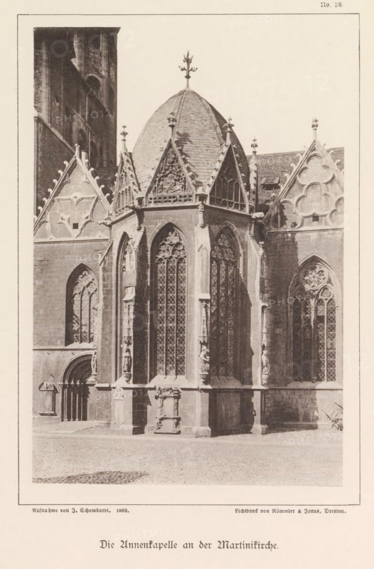 Exterior of the Anna Chapel of St. Martin's Church in Braunschweig, Die Annenkapelle an der Martinikirche, Braunschweig's Baudenkmäler, page, photomechanical print, number: 'No. 28.', photographer: J. Schombardt, Braunschweig, cliché maker: Römmler & Jonas, Dresden, publisher: Benno und Wilhelm Danert Goeritz, 1892, Lower Saxony, Saxony, paper, collotype, photoprint, height 156 mm x width 104 mm, facade (of house or building), parts of church exterior and annexes: chapel, St. Martin's Church (Braunschweig), A sepia-toned photograph of a gothic chapel exterior showing a central octagonal apse with a steep conical roof topped by a decorative finial, flanked by pointed gables and mullioned windows with intricate tracery. The apse has tall, narrow arched windows with patterned leaded glass set between sculpted vertical buttresses that feature carved figures and decorative niches. The surrounding walls display ornamental quatrefoil and trefoil motifs, steeply pitched rooflines with finials,...