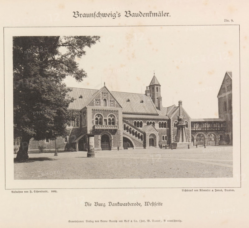 Western facade of the castle Dankwarderode in Braunschweig, Die Burg Dankwarderode, Westseite, Braunschweig's Baudenkmäler, page, photomechanical print, number: 'No. 9.', photographer: J. Schombardt, Braunschweig, cliché maker: Römmler & Jonas, Dresden, publisher: Benno und Wilhelm Danert Goeritz, 1892, J. Schombardt, Römmler & Jonas, Benno und Wilhelm Danert Goeritz, photographer, cliché maker, publisher, Lower Saxony, Saxony, paper, collotype, photoprint, height 102 mm x width 154 mm, castle, facade (of house or building), Dankwarderode, A sepia-toned photograph shows a large stone building with arched windows and decorative brickwork, featuring a steep metal roof, a stepped staircase along the facade, and a turret with a conical top; a tree with dense foliage partly frames the left side while a paved open square stretches across the foreground; a statue mounted on a tall plinth stands near the building and a covered walkway with arched openings connects sections of the structure.