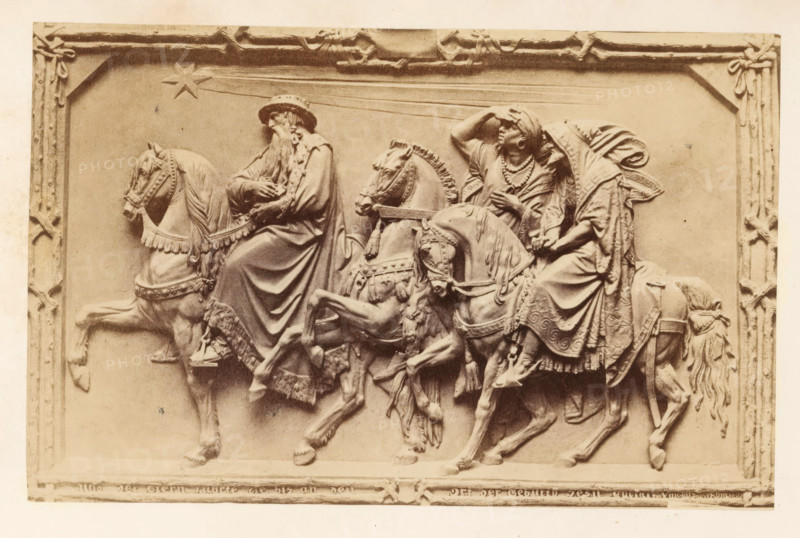 Relief depicting the three wise men, photograph, page, c. 1863 - in or before 1868, photographer, paper, albumen print, height 97 mm x width 151 mm, Photo on frontispiece., the story of the three Wise Men (kings or Magi) (Matthew 2:1-12), sculpture (relief, sculpture), A rectangular relief panel framed with a decorative border shows three robed figures seated on horses moving to the right, each horse wearing ornate bridles and decorative trappings. The leftmost rider wears a wide-brimmed hat and long flowing beard, with draped clothing that falls over the horse’s flank; the central rider has a raised arm shading the eyes and layered garments with necklaces, while the rightmost rider has a head covering and a cloak with patterned edges, leaning slightly forward. The horses display detailed musculature and flowing manes and tails, with harnesses, tassels, and patterned saddle cloths. Above the riders a star with trailing lines appears in the upper area of the panel. The overall tone is s...