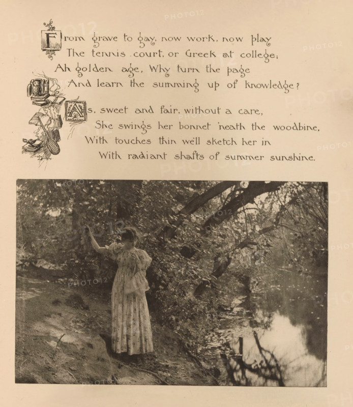 Woman on a waterfront with trees, page, photomechanical print, photographer: Mary Bartlett, United States of America, cliché maker: anonymous, c. 1884 - in or before 1894, North America, paper, photoaquatint, height 109 mm x width 165 mm, adolescent, young woman, maiden, river bank, A sepia-toned page showing a decorative printed poem at the top with ornate initial letters and small illustrative flourishes along the left margin above a large photograph; the photograph depicts a person in a long patterned dress standing on a sloped, leaf-strewn riverbank beneath overhanging tree branches, with water reflecting branches and light in the foreground and foliage and roots along the shore.