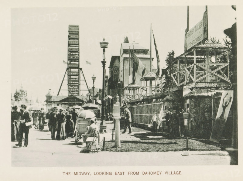 View of a street with national pavilions and a Ferris wheel at the World's Columbian Exposition in Chicago in 1893, The Midway, looking east from Dahomey village, page, photomechanical print, number: 'Plate 107', photographer: Charles Dudley Arnold, Chicago, photographer: HD Higinbotham, clichémaker: anonymous, 1893, Charles Dudley Arnold, HD Higinbotham, photographer, clichémaker, North America, Illinois, paper, collotype, photogravure, height 134 mm x width 190 mm, world fair, world exhibition, giant wheel, Ferris wheel, World's Columbian Exposition, A crowded outdoor scene with many people walking and standing along a wide pathway, several holding umbrellas and wearing hats and early twentieth-century clothing, a person seated on a bench beside a baby carriage, a tall Ferris wheel structure visible in the background near ornamental lamp posts, a row of buildings and wooden viewing platforms with railings and flags flying from poles, trees behind the structures, and a freestanding ca...