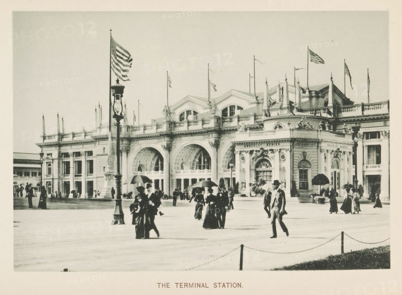 The terminal Station, View of the train station at the World's Columbian Exposition in Chicago in 1893, page, photomechanical print, number: 'Plate 36', photographer: Charles Dudley Arnold, Chicago, photographer: HD Higinbotham, cliché maker: anonymous, 1893, Charles Dudley Arnold, HD Higinbotham, photographer, cliché maker, North America, Illinois, paper, collotype, photoprint, height 132 mm x width 192 mm, station, shelter (railway, tramway), world fair, world exhibition, World's Columbian Exposition, A wide facade of a grand stone building with ornate arches, columns, balustrades, and sculptural decorations stretches across the scene, topped by decorative rooflines and several flagpoles flying flags; in front of the building a tall ornate lamp post stands near the center foreground while groups of people in period clothing and hats walk and gather across a broad open paved plaza, some carrying umbrellas and some conversing, with a low chain barrier and grassy edge visible along the ...