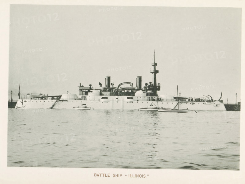Battleship Illinois at the World's Columbian Exposition in Chicago in 1893, Battle ship 'Illinois', page, photomechanical print, number: 'Plate 69', photographer: Charles Dudley Arnold, Chicago, photographer: HD Higinbotham, cliché maker: anonymous, 1893, Charles Dudley Arnold, HD Higinbotham, photographer, cliché maker, North America, Illinois, paper, collotype, photoprint, height 133 mm x width 190 mm, ships (in general), world fair, world exhibition, World's Columbian Exposition, A large naval ship sits on calm water with a long low hull and multiple rounded turrets and openings along its side, a central superstructure with smokestacks and curved piping, a tall mast with platform near the top, and small boats floating nearby; people are visible on the ship's decks and near railings, flags fly at the bow and stern, and a pier extends behind the stern with lamp posts.