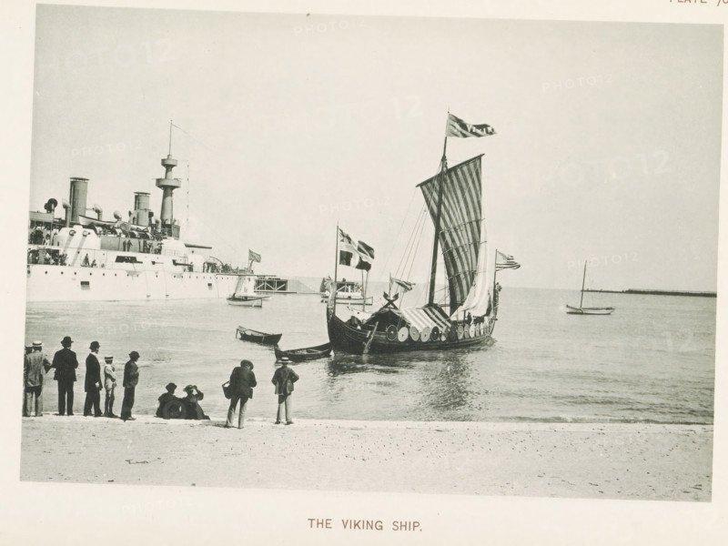 The Viking Ship, Viking ship in the water at the World's Columbian Exposition in Chicago in 1893, page, photomechanical print, number: 'Plate 70', photographer: Charles Dudley Arnold, Chicago, photographer: HD Higinbotham, cliché maker: anonymous, 1893, Charles Dudley Arnold, HD Higinbotham, photographer, cliché maker, North America, Illinois, paper, collotype, light printing, height 131 mm x width 191 mm, ships (in general), world fair, world exhibition, World's Columbian Exposition, A shoreline scene showing a sailboat with a large patterned sail and shields along its hull floating near the water, with flags flying from its mast and small rowboats nearby; a large steamship with funnels and deck structures is moored in the background to the left, and a group of people in period clothing stand and sit along the beach in the foreground watching the boats.