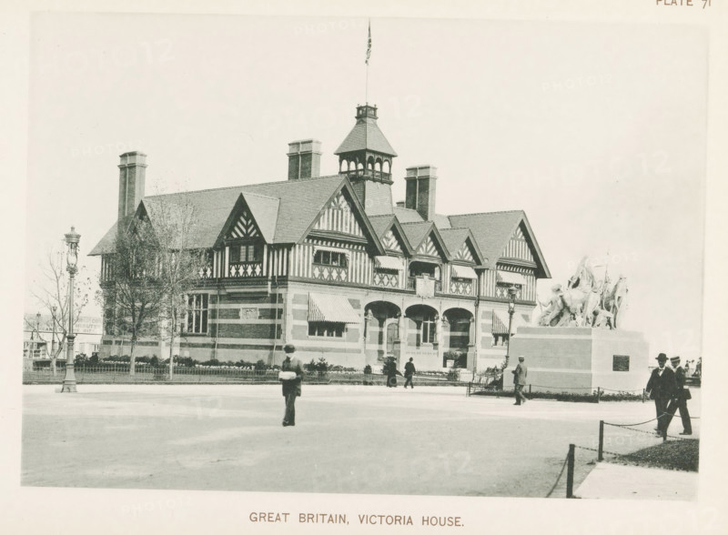Great Britain, Victoria House, View of Victoria House, the Great Britain pavilion at the World's Columbian Exposition in Chicago in 1893, page, photomechanical print, number: 'Plate 71', photographer: Charles Dudley Arnold, Chicago, photographer: HD Higinbotham, clichémaker: anonymous, 1893, Charles Dudley Arnold, HD Higinbotham, photographer, clichémaker, North America, Illinois, paper, collotype, photogravure, height 133 mm x width 190 mm, world fair, world exhibition, World's Columbian Exposition, A large ornate building with patterned half-timbered upper walls and a steep tiled roof topped by a small tower with open arches and a flagpole sits behind a low fence and planted shrubbery, flanked by tall chimneys and a lamppost; in front of the building a raised stone pedestal supports a sculptural group of figures and animals, and several people in period clothing walk or stand on the paved foreground, one person blurred in motion near the center.