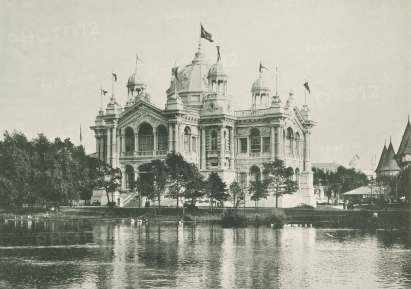 The Brazilian Building at the World's Columbian Exposition in Chicago in 1893, page, photomechanical print, number: 'Plate 74', photographer: Charles Dudley Arnold, Chicago, photographer: HD Higinbotham, cliché maker: anonymous, 1893, Charles Dudley Arnold, HD Higinbotham, photographer, cliché maker, North America, Illinois, paper, collotype, light printing, height 134 mm x width 190 mm, world fair, world exhibition, World's Columbian Exposition, A large ornate building with domes and towers stands behind a row of trees at the edge of a calm body of water, its reflection visible on the water surface; the façade shows arched windows, columns, decorative sculptures, and flags flying atop several roof elements, while small groups of people and a staircase appear near the building and a pavilion with pointed roofs is visible to the right.