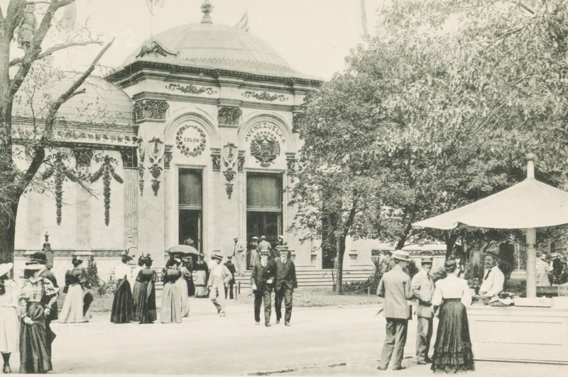 Government Building, Venezuela, Pavilion of Venezuela at the World's Columbian Exposition in Chicago in 1893, page, photomechanical print, number: 'Plate 76', photographer: Charles Dudley Arnold, Chicago, photographer: HD Higinbotham, cliché maker: anonymous, 1893, Charles Dudley Arnold, HD Higinbotham, photographer, cliché maker, North America, Illinois, paper, collotype, photoprint, height 133 mm x width 191 mm, world fair, world exhibition, World's Columbian Exposition, A sepia-toned scene shows an ornate building facade with decorative arches, columns, and a domed roof, flanked by trees; people in period clothing, including long skirts, hats, and suits, stand, walk, and gather in front of the entrance and on the steps, while a group near a canopy or umbrella appears to be conversing; architectural details include wreath motifs and sculpted ornaments above tall doorways, and foliage partially obscures the right side of the building.