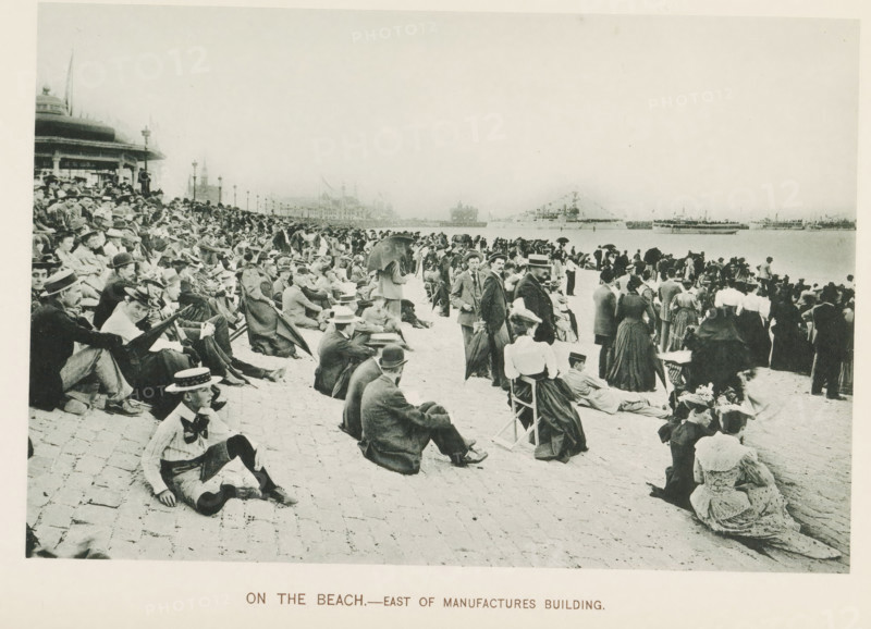 On the beach.- East of Manufactures Building, People watching ships from a quay during the World's Columbian Exposition in Chicago in 1893, page, photomechanical print, number: 'Plate 80', photographer: Charles Dudley Arnold, Chicago, photographer: HD Higinbotham, cliché maker: anonymous, 1893, Charles Dudley Arnold, HD Higinbotham, photographer, cliché maker, North America, Illinois, paper, collotype, photoprint, height 129 mm x width 191 mm, ships (in general), quay, world fair, world exhibition, World's Columbian Exposition, A wide beachfront scene shows a large crowd of people seated and standing along a paved shore facing the water, many wearing period clothing with hats, suits, long dresses, and coats; some individuals are seated on folding chairs or the pavement while others stand in small groups or lean on umbrellas, and a few hold parasols; in the background there are buildings and lamp posts along a promenade and ships visible on the water, including a decorated vessel with f...