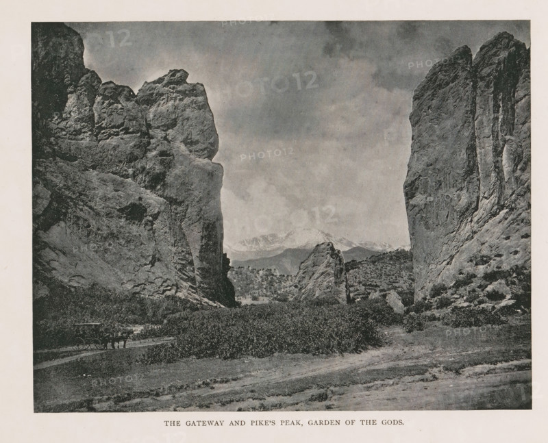 The gateway and Pike's Peak, Garden of the Gods, View of the rock formations of the Garden of the Gods and Pikes Peak, page, photomechanical print, Colorado Springs, cliché maker: New York Photo-Gravure Company, New York (city), c. 1888 - in or before 1893, New York Photo-Gravure Company, photographer, cliché maker, North America, Colorado, paper, autotypie, height 158 mm x width 202 mm, mountain-range, snow peaks, rock-formations, A black and white photograph showing a rocky landscape with two tall rock formations framing a central gap, rugged cliff faces with textured surfaces and vertical striations on either side, smaller rock outcrops and boulders in the middle distance, a flat plain with low vegetation and bushes in the foreground, a narrow dirt path winding through the scene, distant mountains visible through the gap under a cloudy sky, and a horse-drawn wagon on the path near the left rock face.