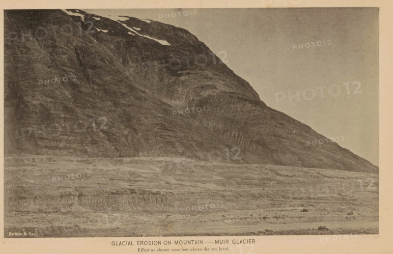 Glacial erosion on mountain, Muir Glacier, View of the glacial grooves of the Muir Glacier, page, photomechanical print, inscription: 'Effect as shown 1000 feet above the sea level.', inscription: 'Britton & Rey', cliché maker: Britton & Rey, New York (city), c. 1885 - in or before 1890, photographer, North America, Alaska, Skagway-Hoonah-Angoon, paper, collotype, photoprint, height 112 mm x width 185 mm, mountains, glacier, A wide, monochrome image of a steep, rocky mountainside with striated rock faces and patches of snow near the top, rising from a flat, layered foreground of textured terrain and sparse scattered rocks, under a blank sky.