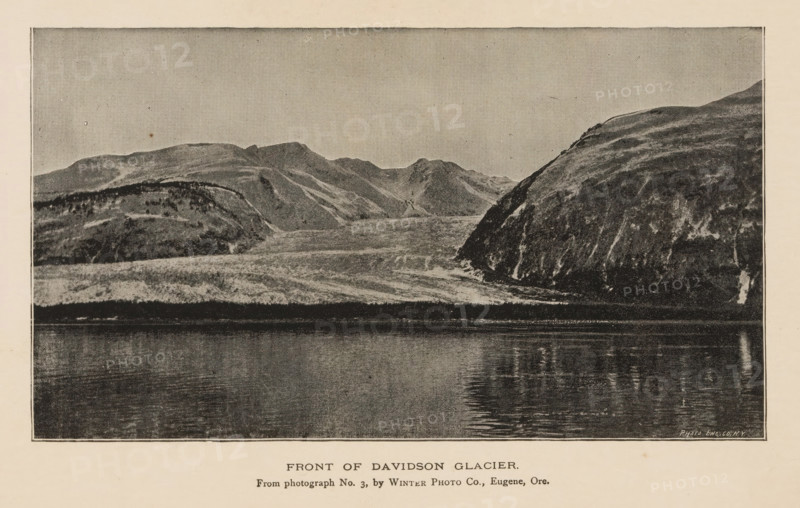 Front of Davidson Glacier, View of the Davidson Glacier, page, photomechanical print, inscription: 'From photograph No. 3, by Winter Photo Co., Eugene, Ore.', photographer: Winter Photo Co., Haines, cliché maker: Photo-Engraving Co., New York (city), c. 1885 - in or before 1890, North America, Alaska, paper, autotypie, height 95 mm x width 168 mm, glacier, Davidson Glacier, A grayscale image showing a wide body of calm water in the foreground reflecting ripples and darker vertical reflections, with a rocky shoreline rising behind it into layered hills and rugged slopes; the hills exhibit varied textures with lighter and darker patches and streaked surfaces, and a prominent steep, darker cliff appears on the right side.