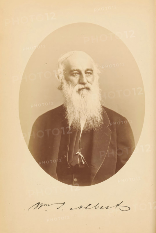 Wm. J. Albert, Portrait of William Julian Albert, photograph, page, photographer: Bendann Bros., c. 1866 - in or before 1871, paper, albumen print, height 148 mm x width 115 mm, Person, William Julian Albert, historical persons, A sepia-toned oval portrait of an older man with a long white beard and thinning hair, shown from the chest up and wearing a dark suit jacket over a vest and a narrow tie, his face turned slightly to one side with a neutral expression, set against a plain background within a light rectangular matte.
