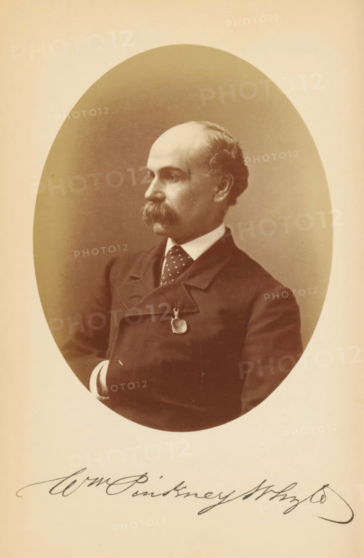 Portrait of William Pinkney Whyte, Wm. Pinkney Whyte, photograph, page, photographer: Bendann Bros., c. 1866 - in or before 1871, paper, albumen print, height 147 mm x width 114 mm, Person, William Pinkney Whyte, historical persons, A sepia-toned oval portrait of a man shown from the chest up, turned in three-quarter profile to his left, with a receding hairline and a thick mustache, wearing a dark double-breasted coat over a white shirt and a dotted tie, a round pendant hanging from a chain at his chest, his right arm bent with a visible cuff, set against a darker oval background framed by a lighter border.