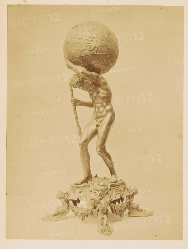 Silver Atlas figurine by one of the Van Vianen brothers, Silver Atlas figurine, crafted by van Vianen, photograph, page, number: 'No. 3359.', photographer: Pieter Oosterhuis, Amsterdam, 1876, paper, albumen print, height 167 mm x width 125 mm, Photo on fourth unnumbered page after page 204., piece of sculpture, reproduction of a piece of sculpture, Atlas supporting the heavens on his shoulders, Historical Exhibition Amsterdam, Oudemannenhuis (Amsterdam), Period, A sepia-toned photograph shows a tall sculpted male figure standing on an ornate base, the figure holding a staff and leaning forward as he supports a large decorative globe on his shoulders; the globe has raised relief designs and the man's muscular form, detailed facial hair, and defined limbs are visible, while the base beneath him features carved cherubic figures, scrollwork, and decorative garlands.