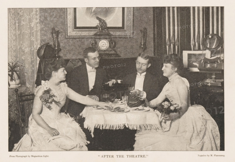 Two men and two women sit at a table in an entertainment venue, 'After the Theater', page, photomechanical print, inscription: 'From Photograph by Magnesium Light.', photographer: M. Flammang, cliché maker: anonymous, c. 1884 - in or before 1889, paper, autotypie, height 100 mm x width 151 mm, inn, coffee-house, public house, adult woman, adult man, A black and white scene of four people seated around a small table covered with a fringed tablecloth, with two women in light-colored dresses holding small bouquets on opposite sides and two men in dark formal jackets seated between them; the table holds plates, glasses, and a small teapot or coffee pot being handled by one man, while the other man looks toward him; behind them is a mantel with an ornate clock topped by a small statuette, flanked by decorative objects and framed artwork above, with patterned curtains and a potted plant visible at the sides.