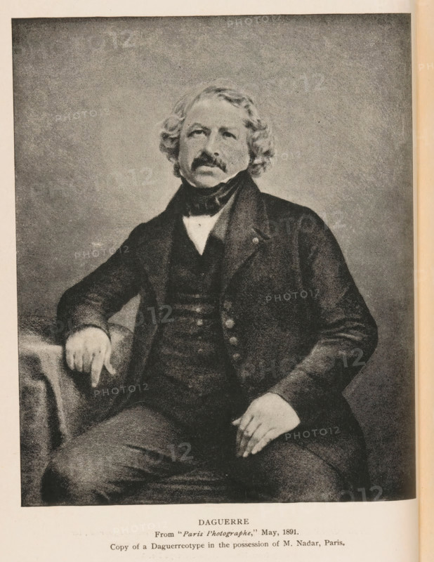 Daguerre, Reproduction of a daguerreotype by Louis Jacques Mandé Daguerre by John Adams Whipple, reproduction, page, photomechanical print, inscription: 'From 'Paris Photographe, ' May, 1891, Copy of a Daguerreotype in the possession of M. Nadar, Paris', cliché maker: Kurtz, after photo by John Adams Whipple (possibly), 1887 - 1907, John Adams Whipple, photographer, paper, autotypie, height 149 mm x width 118 mm, Person, Louis Jacques Mandé Daguerre, historical persons, A monochrome portrait of a seated man with wavy hair and a mustache, wearing a dark suit with a high collar and cravat; his left arm rests on a draped surface while his right hand rests on his thigh, and the background is a plain, textured backdrop.