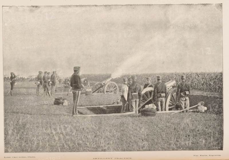Military exercise with artillery, Artillery practice, page, photomechanical print, inscription: 'Kurtz', photographer: Carl Hiller, cliché maker: Kurtz, 1887 - 1907, paper, autotypie, height 115 mm x width 171 mm, artillery range, firing range, shooting range, military training, warfare, military affairs, A group of uniformed men stand in a grassy field around large wheeled cannons with smoke emerging from one barrel, some men facing the artillery and others turned slightly away, with sacks and equipment on the ground near shallow dugouts; in the background more figures and distant lines of vegetation are visible under a wide sky.
