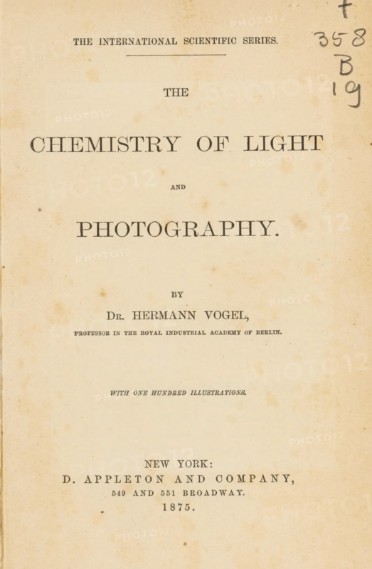 The chemistry of light and photography, book, annotation: 'FEB 1982', bookplate: 'SFJ ex libris', writer (clerical worker): Hermann Wilhelm Vogel, publisher: D. Appleton and Company, New York (city), 1875, writer (clerical worker), North America, pasteboard, paper, textile materials, printing, wood engraving, galvanoplasty, photoaquatint, collotype, height 195 mm x width 135 mm x thickness 23 mm, A faded cream-colored book page with aged spots and discoloration, centered large serif title text across the top half, a horizontal rule near the top, smaller lines of serif text arranged vertically down the page, a vertical handwritten pencil mark and numerals near the upper right edge, and more serif text grouped toward the lower half above a blank lower margin.