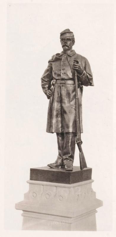 View of a detail of the civil war monument in Manchester, member of the infantry, page, photomechanical print, c. 1875 - in or before 1880, paper, collotype, photoprint, height 194 mm x width 91 mm, Print three pages after page 39., the soldier, the soldier's life, monument, statue, A full-length statue of a uniformed soldier standing on a multi-tiered pedestal, wearing a cap and a long coat with a belted waist, one hand resting on his hip and the other holding a rifle that stands upright beside him, with detailed facial features including a mustache, boots visible at the base of the coat, and the pedestal showing carved circular motifs and layered molding.