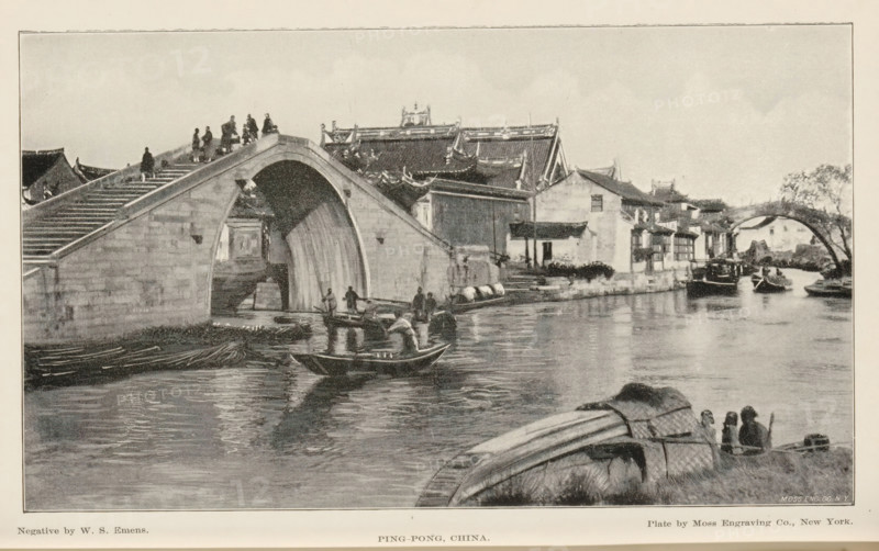 Ping-pong, China, page, photomechanical print, photographer: WS Emens, Shanghai, cliché maker: Moss Engraving Co., New York, c. 1888 - in or before 1893, North America, paper, autotypie, height 109 mm x width 186 mm, canals, waters (in city), bridge, A riverside scene showing a large stone arch bridge with steep steps and several people standing and walking on it, a smaller arched bridge visible in the distance, boats of different sizes on the water with people rowing or sitting in them, buildings with tiled roofs and decorative rooflines along the riverbank, reflections of the bridge and boats on the water surface, bundled materials and cargo near the water’s edge, and a foreground view of rounded covered boats and a few seated figures at the riverbank.
